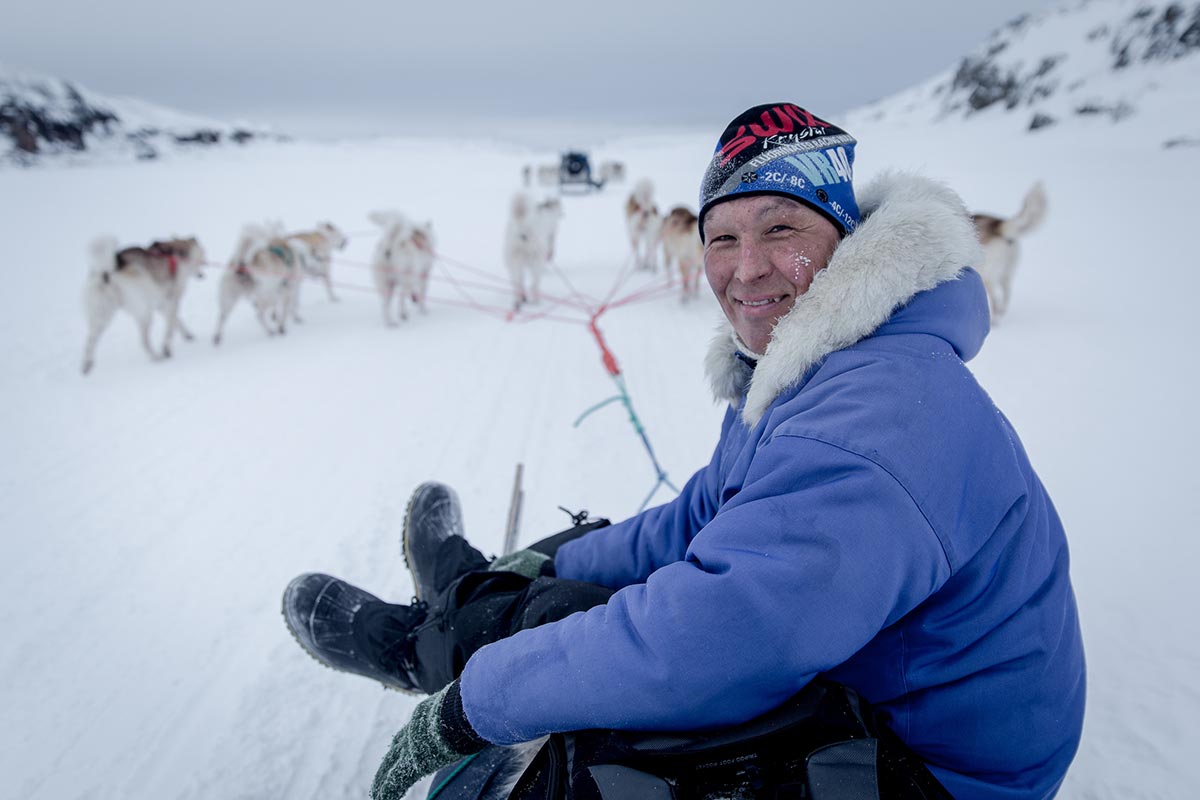 Ritratto di un musher di Ilulissat con la sua slitta e la sua muta di cani