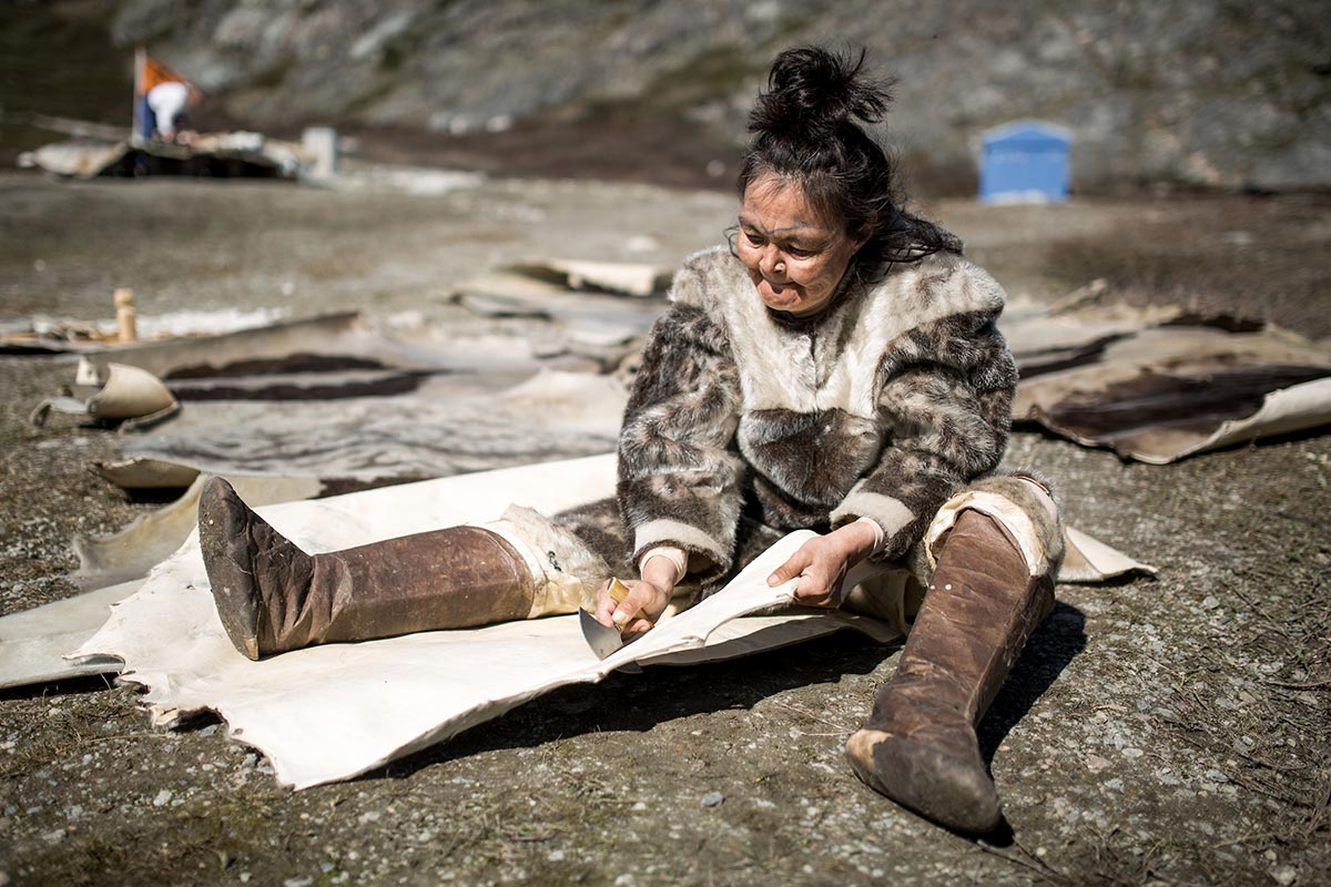 Una donna che lavora la pelle di foca per una tenda nel museo del villaggio vivente di Qasigiannguit in Groenlandia